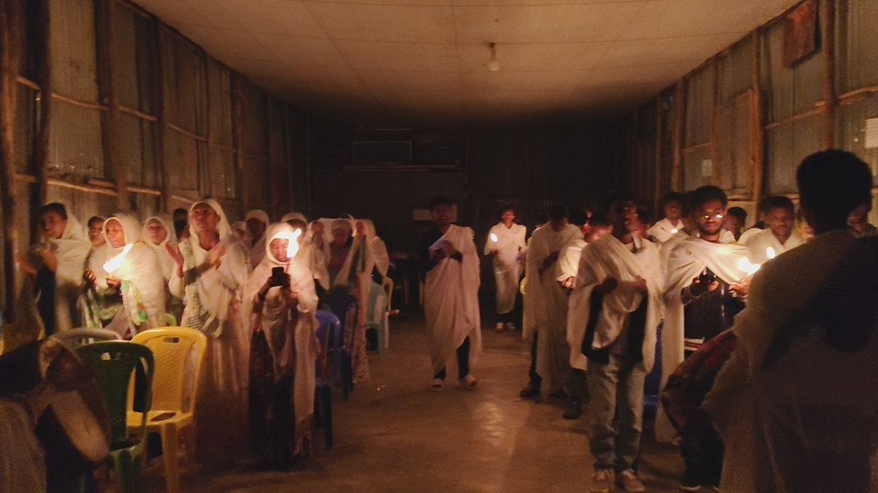 Community members standing with lit candles during a service